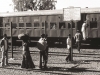 Scene at Kalol Junction station on 12 January 1981. The bi-lingual notice reads, in English:  ‘WESTERN RAILWAY.  NOTICE:  USE THE FOOT BRIDGE.  CROSSING THE LINE IS PROHIBITED’.  But the ticket collector (almost hidden by the passenger in the orange shirt with large bag on his back) knows no one will obey the notice and stands by the gap in the fence to collect the tickets. The passengers have to climb through the carriage and down the other side to gain access to the streets.