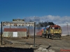 Chile 01: Unter Volllast nehmen die drei GL26C-2 #2009, GL26C-2 #2007 und GT22CU-3 #2404 mit dem täglichen Erzzug zur San Crisobal-Mine Anlauf für den Ascotan-Pass und passieren den Geisterort San Pedro unterhalb des gleichnamigen Vulkans (19.06.2013).