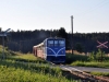 Südböhmen 20: In den Sommermonaten sind die Züge ins Česky Kanada bei Wanderern und Naturfreunden sehr beliebt. Deshalb werden sie stets mit zwei Balm plus Gepäckwagen für den Fahrradtransport gefahren. Eine solche Einheit passiert am Abend des 10.8.2010 gerade den Bahnübergang bei Blažejov.